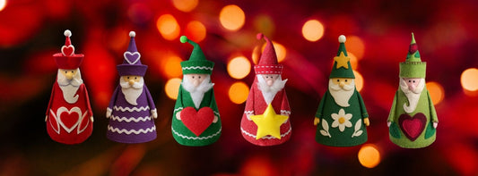 Row of handmade felt Santa decorations in red, green, purple, and white, featuring hearts, stars, and floral designs. Cone-shaped felt Santa ornaments made using a sewing pattern and PDF tutorial.
