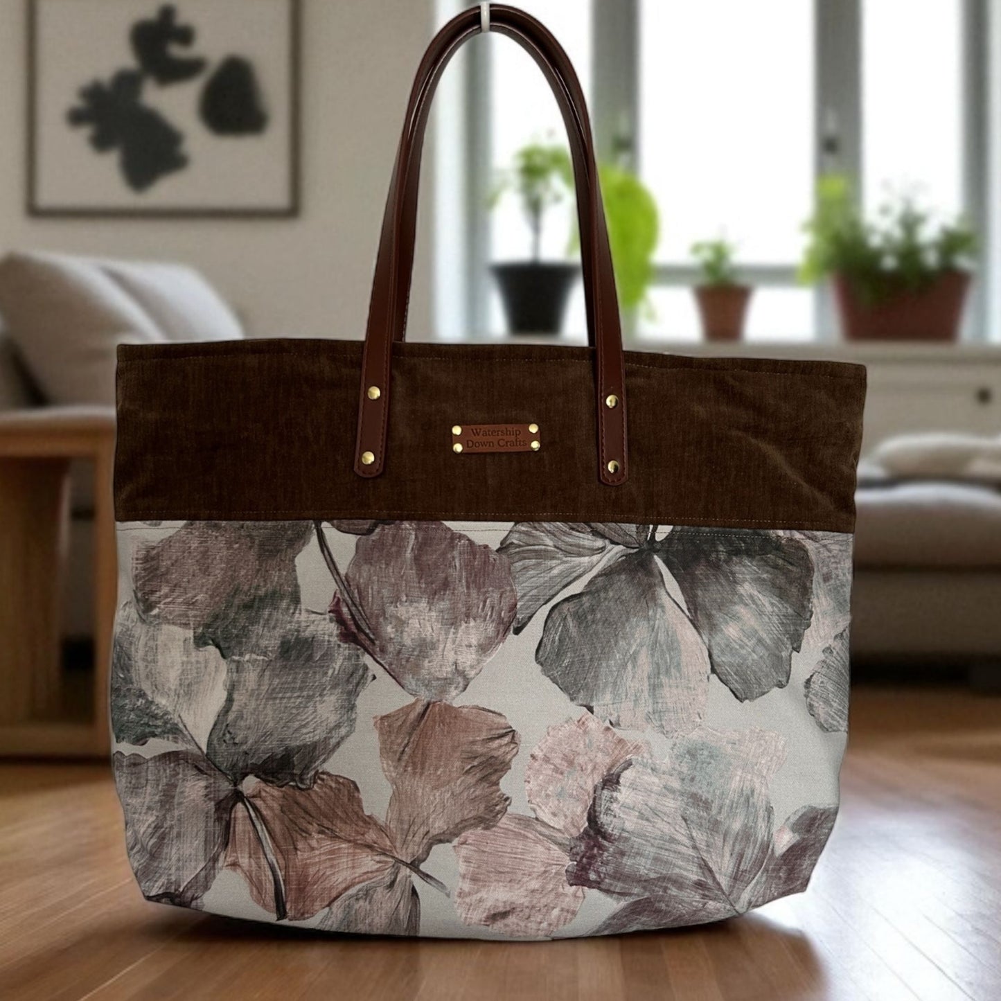 Floral-patterned tote bag with brown handle and trim on a wooden floor.