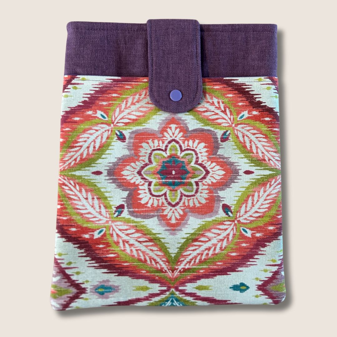 Boho tablet sleeve with a red, green, and plum mandala print, plum contrast panel, and snap closure, made from repurposed fabric