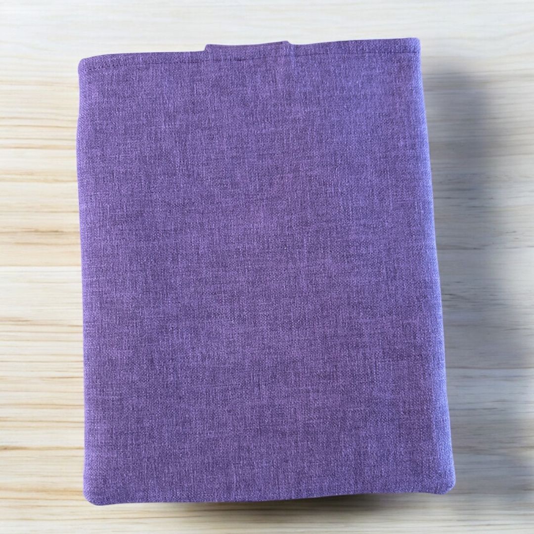 Back view of a tablet sleeve made from deep plum repurposed fabric, shown on a light wooden surface