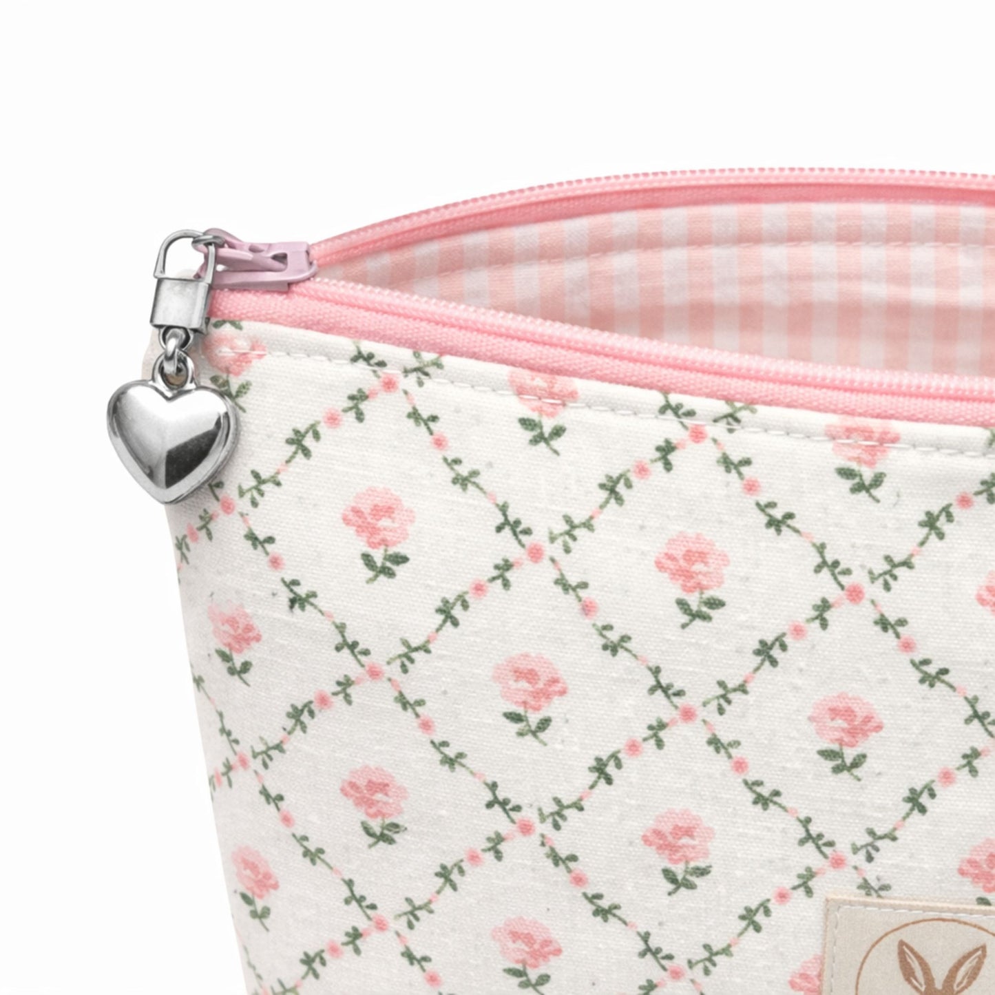 Floral-patterned pouch with pink zipper and heart charm on a white background