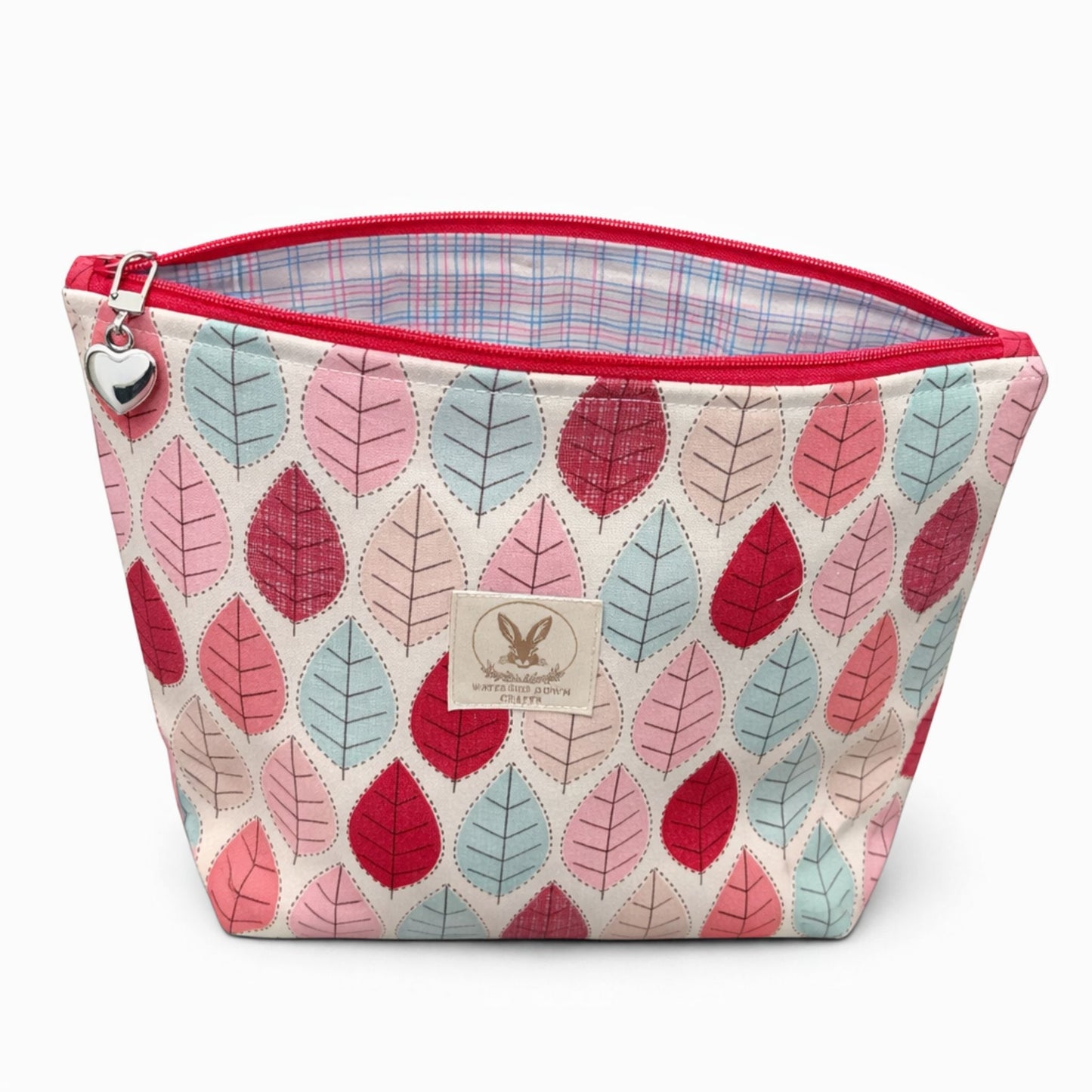 Fabric pouch with leaf pattern and red zipper on a white background