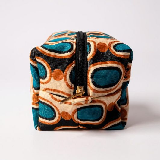 Side view of the boxed pouch showing the structured shape, neat corners, and black zip against the vibrant retro fabric.