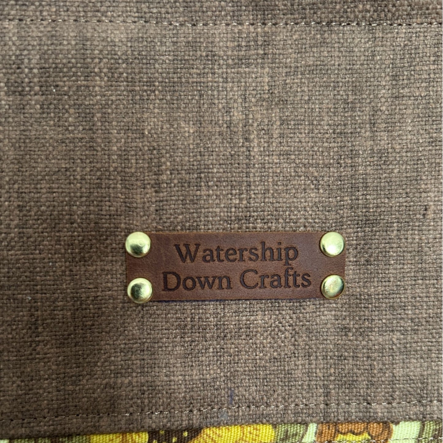 Brown fabric surface with a leather label reading 'Watership Down Crafts'.