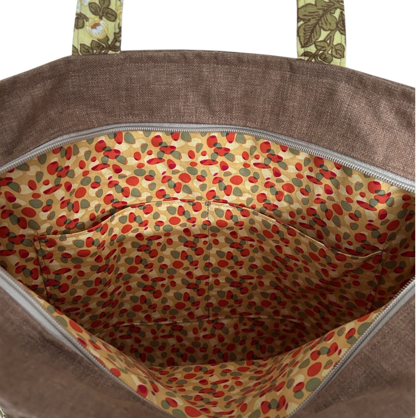 Brown bag with floral handles and a colorful polka dot interior.