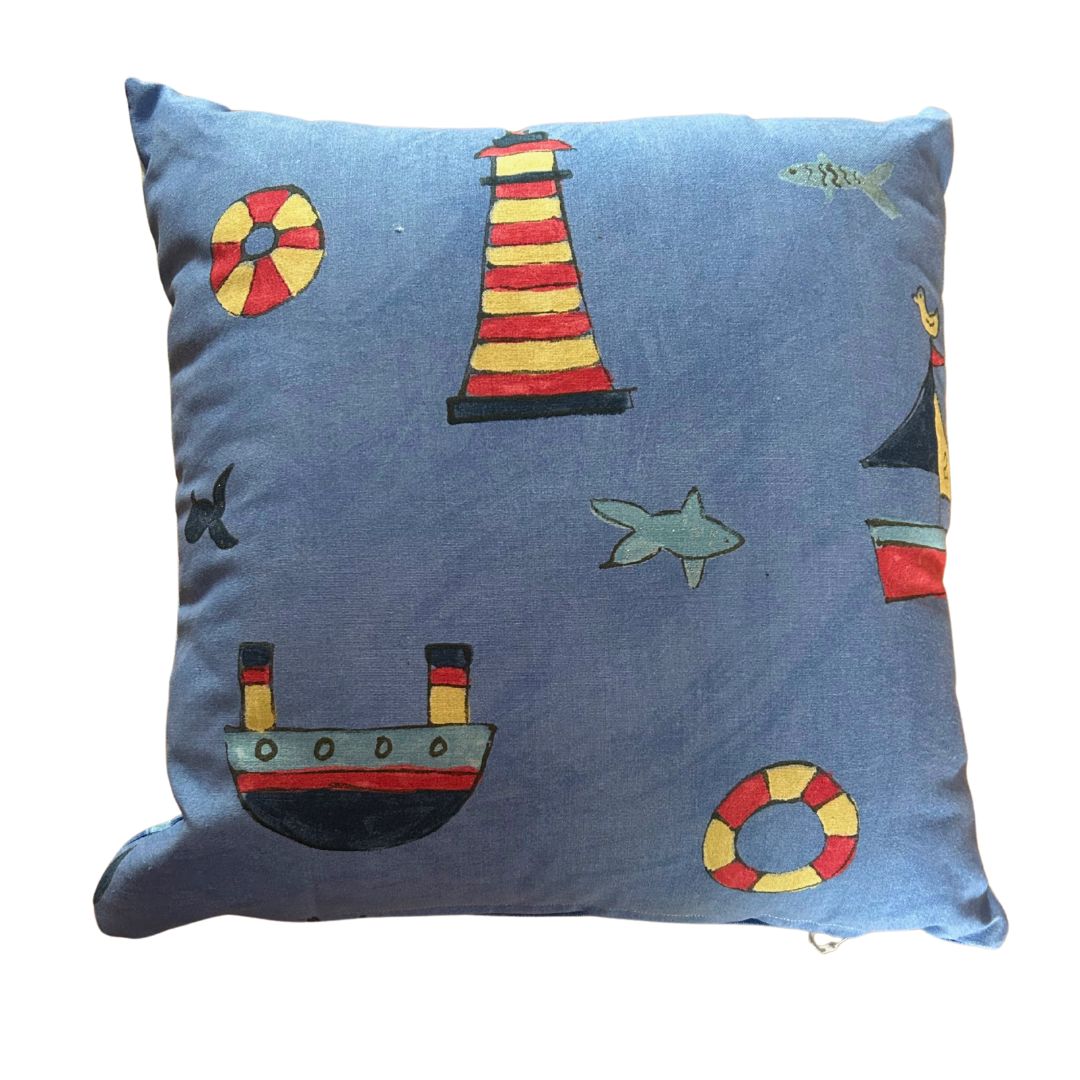 Nautical-themed cushion back with a playful pattern of lighthouses, ships, sharks, and lifebuoys on a denim blue fabric.