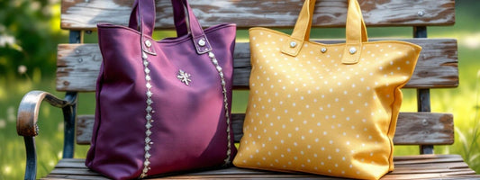 Two colourful tote bags, one purple with decorative trim and one yellow with white polka dots, displayed on a wooden bench outdoors.