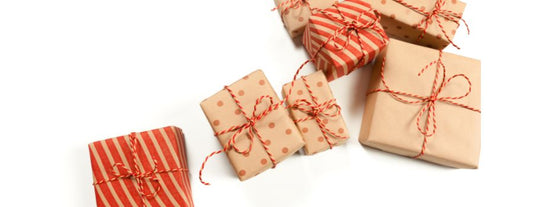 A collection of neatly wrapped gifts in brown and red striped and polka dot wrapping paper, each tied with red and white twine, creating a festive and thoughtful gift presentation.