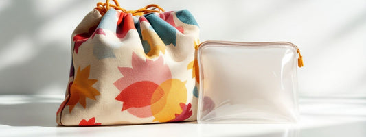 Side-by-side comparison of a handmade fabric drawstring pouch with a bold floral pattern and a clear plastic zip-up bag, displayed on a white surface with soft daylight shadows.