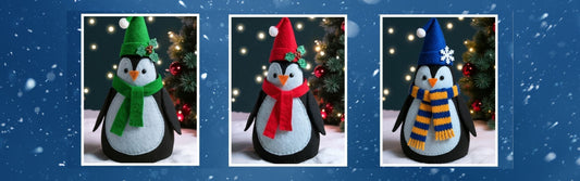 Three handmade felt penguin Christmas ornaments, each with different coloured hats and scarves – green with holly, red with holly, and blue with a snowflake – displayed against a festive background.