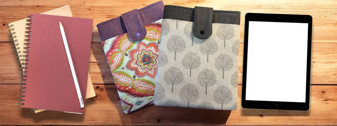 Two handmade tablet sleeves with flap closures shown next to a tablet and spiral notebooks on a wooden table – DIY tech accessory setup.