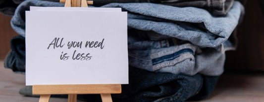 Pile of denim for repurposingwith a sign to say "All you need is less"