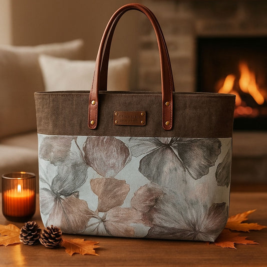 Floral-patterned tote bag on a wooden surface with a candle and leaves, fireplace in the background