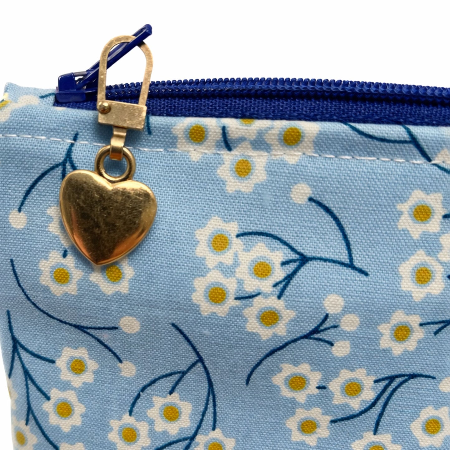 Blue pouch with floral pattern and gold heart charm on a white background