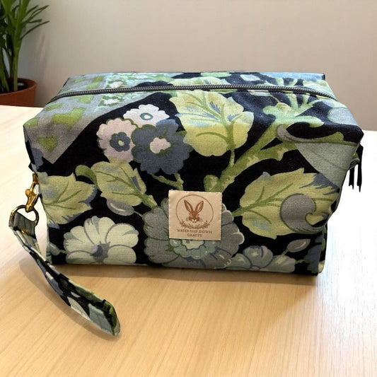 Handmade makeup bag with blue and green vintage floral fabric, black zip, and detachable wrist strap. Made by Watership Down Crafts.