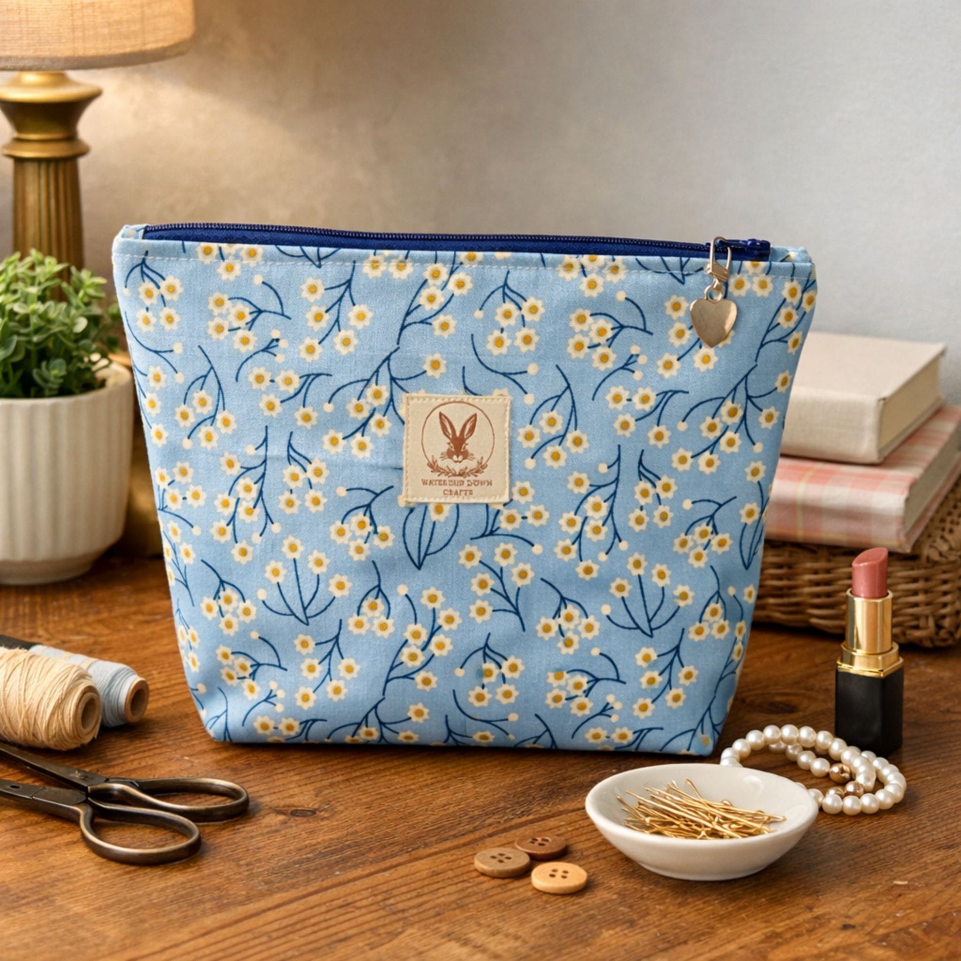 Blue floral-patterned pouch on a wooden surface with stationery items.