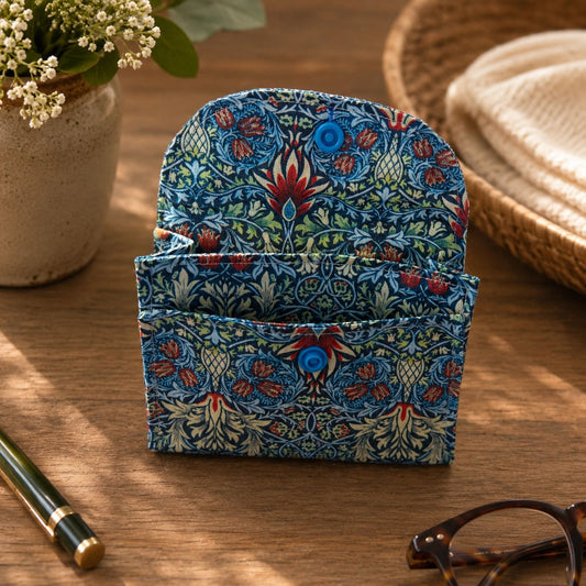 Blue Snakeshead Lily Cotton Card Wallet on a wooden surface with a pen and glasses in the background