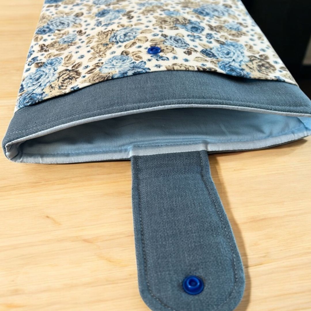 Handmade blue floral tablet sleeve with denim-look trim, blue lining, and snap closure, shown open to reveal soft padded interior.