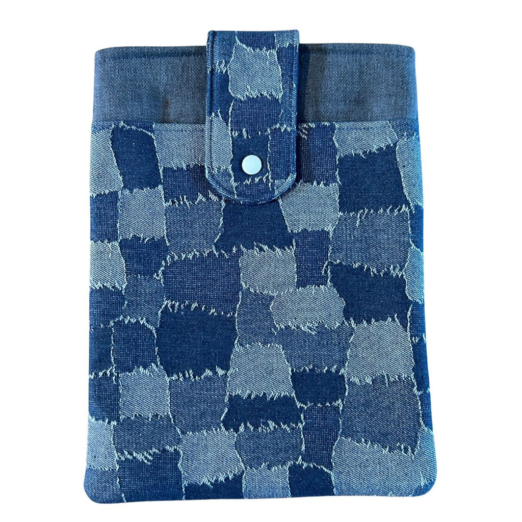 Front view of a denim patchwork print tablet sleeve with a blue snap-tab closure, photographed against a light background.