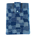 Front view of a denim patchwork print tablet sleeve with a blue snap-tab closure, photographed against a light background.