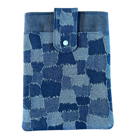 Front view of a denim patchwork print tablet sleeve with a blue snap-tab closure, photographed against a light background.