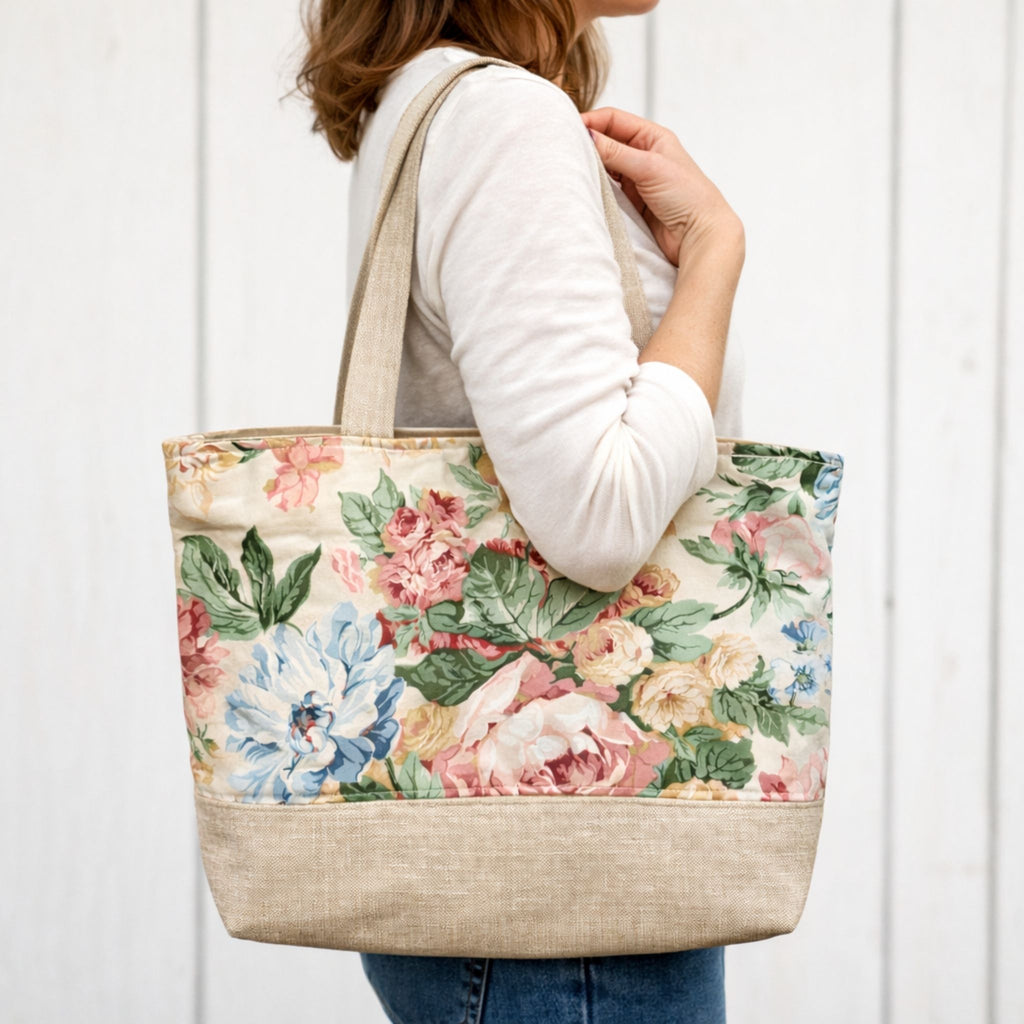 Person holding a floral tote bag against a white background