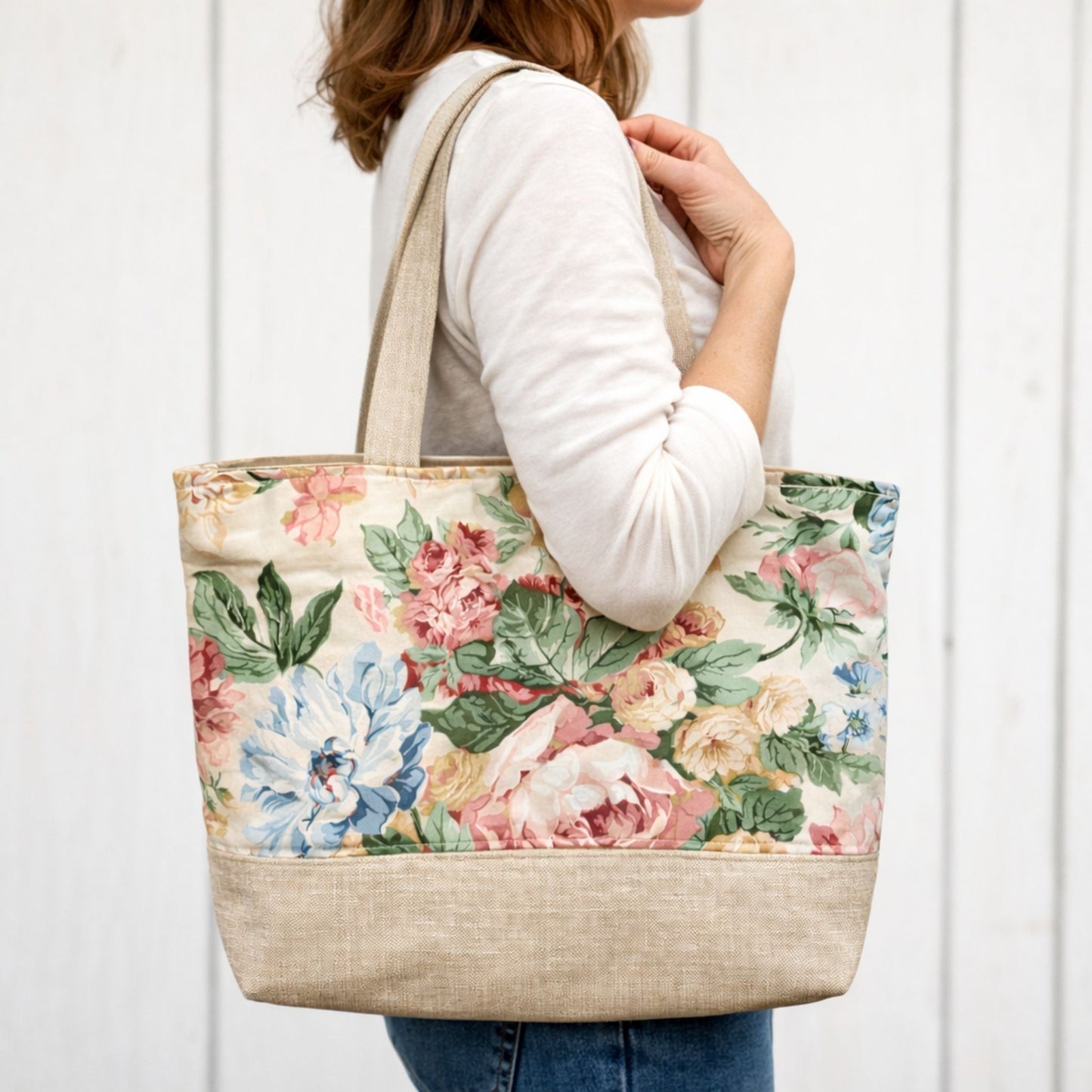 Person holding a floral tote bag against a white background