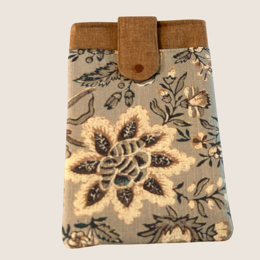 Floral tablet sleeve in taupe, ginger, and cream tones with a snap closure and front pocket, featuring a bold stitched flower design on repurposed fabric