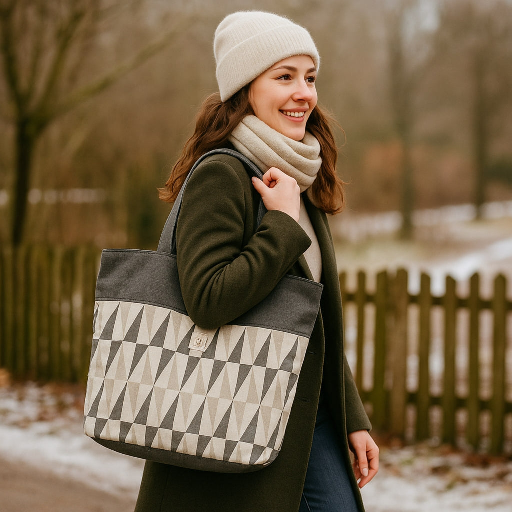 Woman holding a geometric-patterned tote bag outdoors in winter.