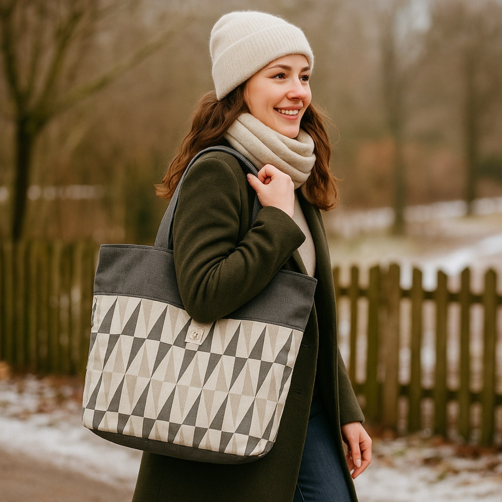 Woman holding a geometric-patterned tote bag outdoors in winter.