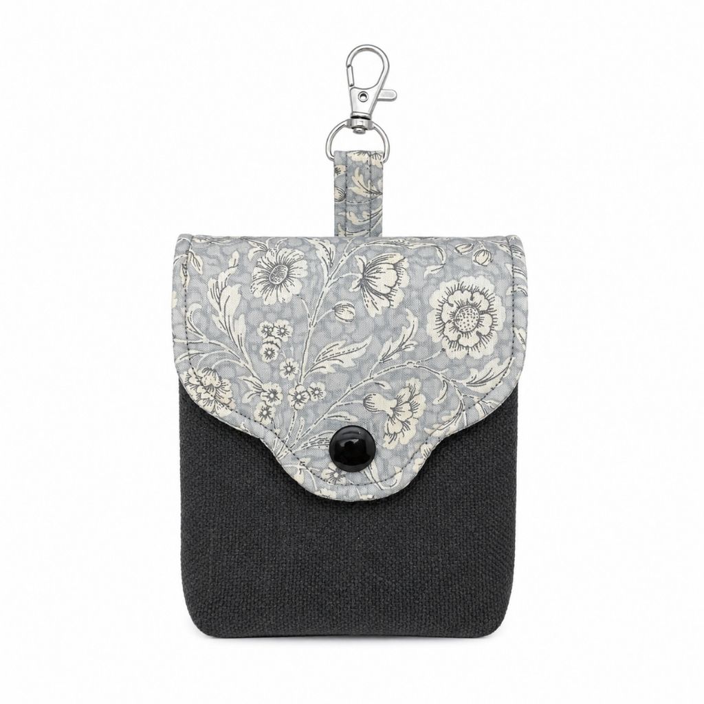 Small pouch with floral patterned flap and dark grey body on a white background