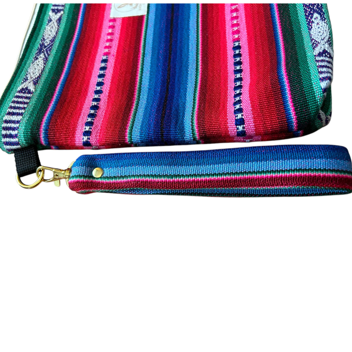 Close-up of a vibrant pink, blue, and green woven zipper pouch featuring a detachable wristlet strap with gold hardware. The intricate patterns and bold colors showcase the unique handmade craftsmanship.