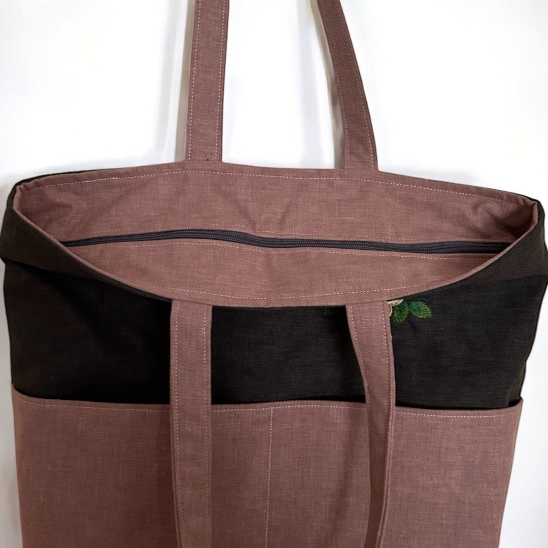 Close-up of a two-tone tote bag with a zip closure and exterior pockets.