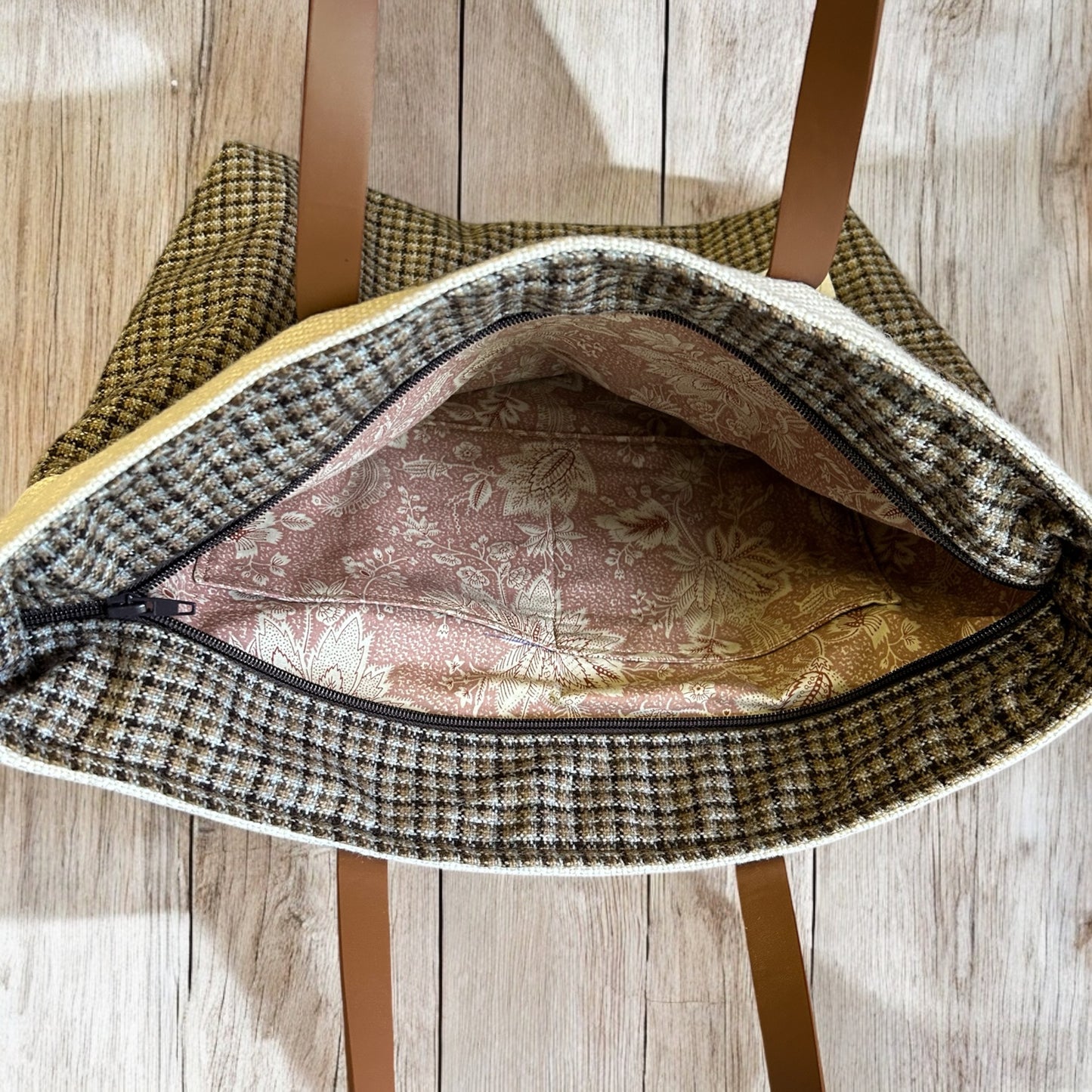 Open tweed tote bag showing a floral-patterned fabric lining and interior pockets