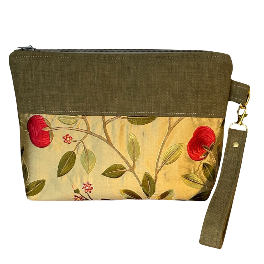 Handmade wristlet pouch in rich olive green and gold, featuring a delicate floral embroidered design with vibrant red blooms. Crafted from rescued fabric offcuts, this eco-friendly clutch includes a detachable strap, secure zipper closure, and gold-tone hardware, making it a stylish and sustainable accessory for everyday use.