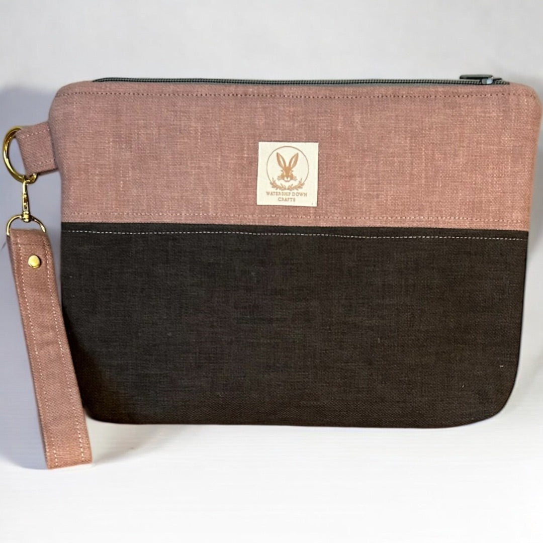 Soft pink and graphite grey handmade wristlet pouch with a detachable strap and secure zipper closure. Crafted from upcycled fabric, this eco-friendly clutch is both stylish and practical for everyday use. Features a minimalist two-tone design with a subtle texture.