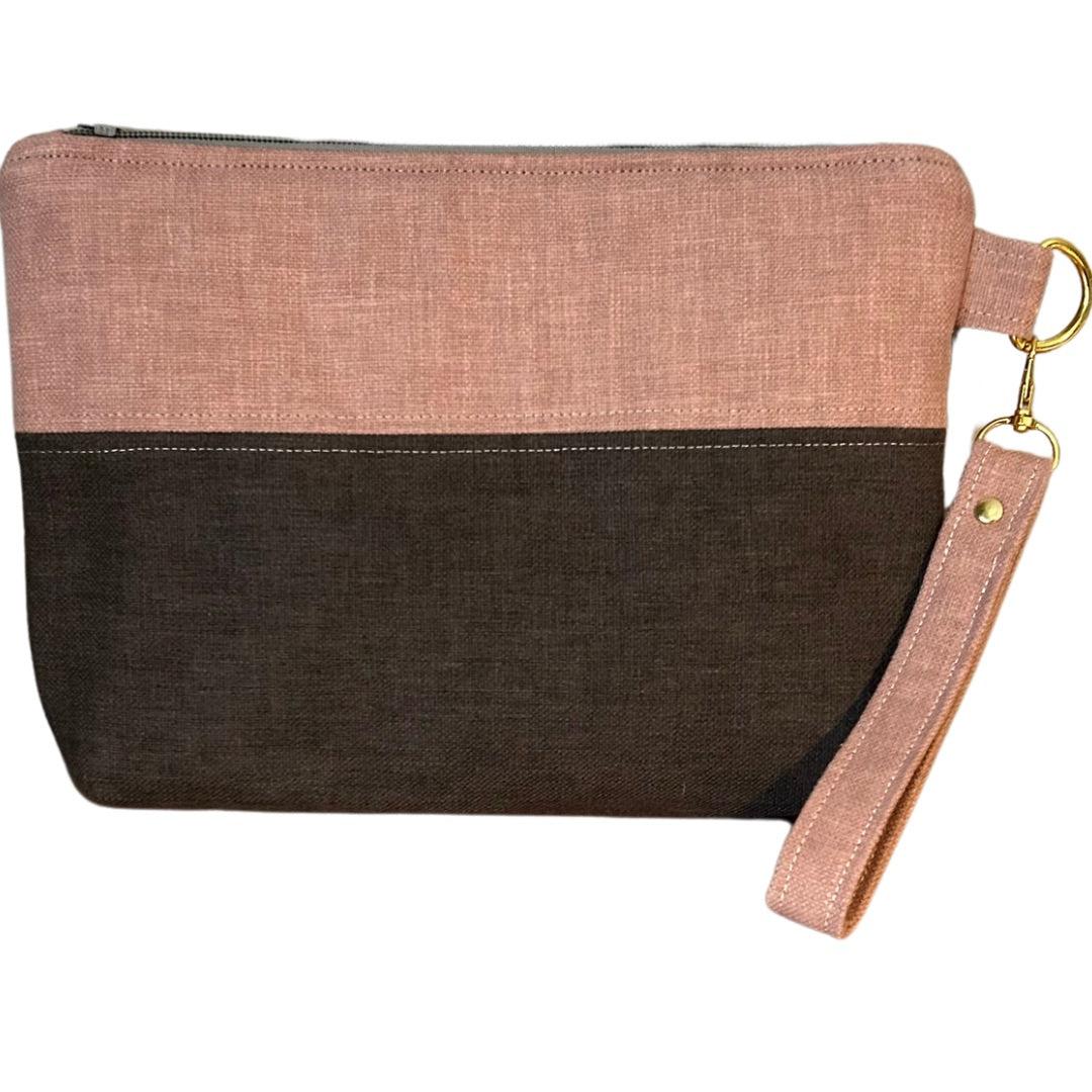 Soft pink and graphite grey handmade wristlet pouch with a detachable strap and gold-tone hardware. Crafted from upcycled fabric, this eco-friendly clutch features a minimalist two-tone design with a secure zipper closure, perfect for everyday essentials.