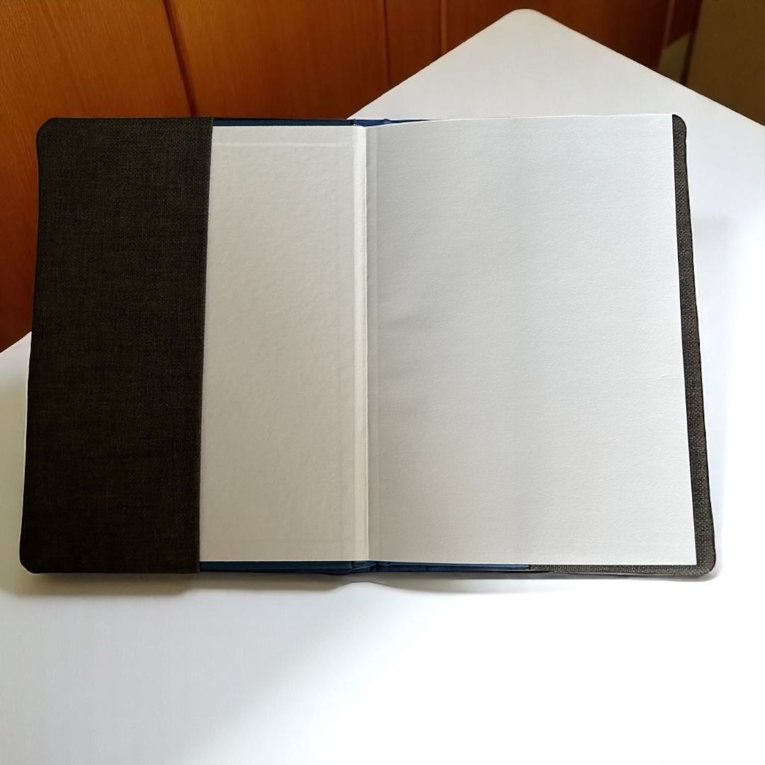 Inside view of the reusable A5 notebook cover, showing the hardback ruled notebook inserted inside with blank open pages.