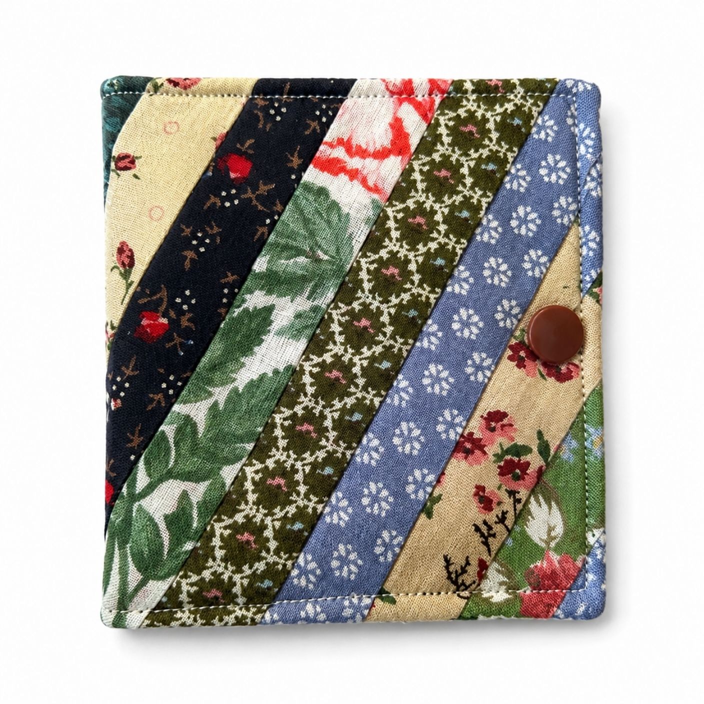 Patchwork-style fabric needle case with floral and geometric patterns on a white background