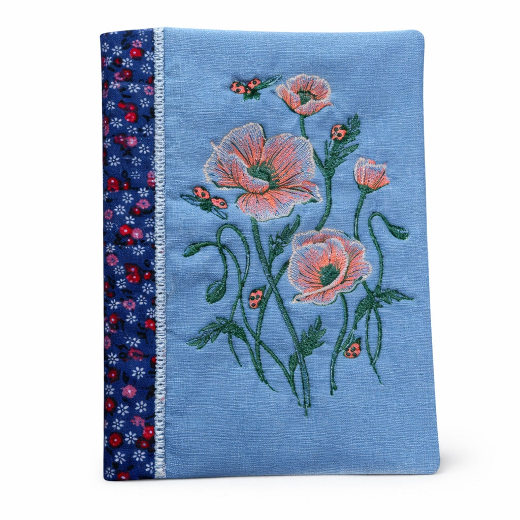 Blue fabric with floral embroidery and ladybug designs on a white background