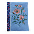 Blue fabric with floral embroidery and ladybug designs on a white background