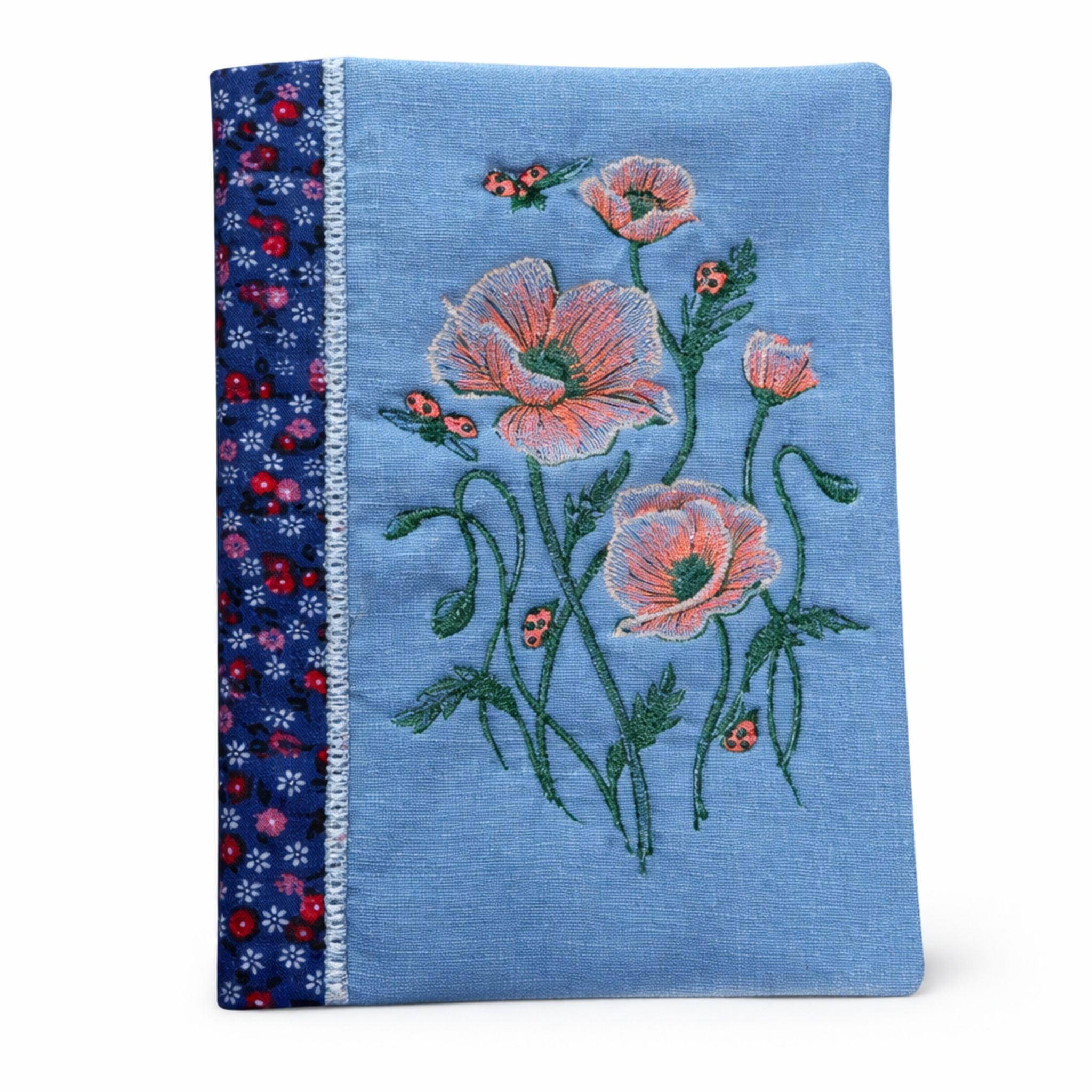 Blue fabric with floral embroidery and ladybug designs on a white background