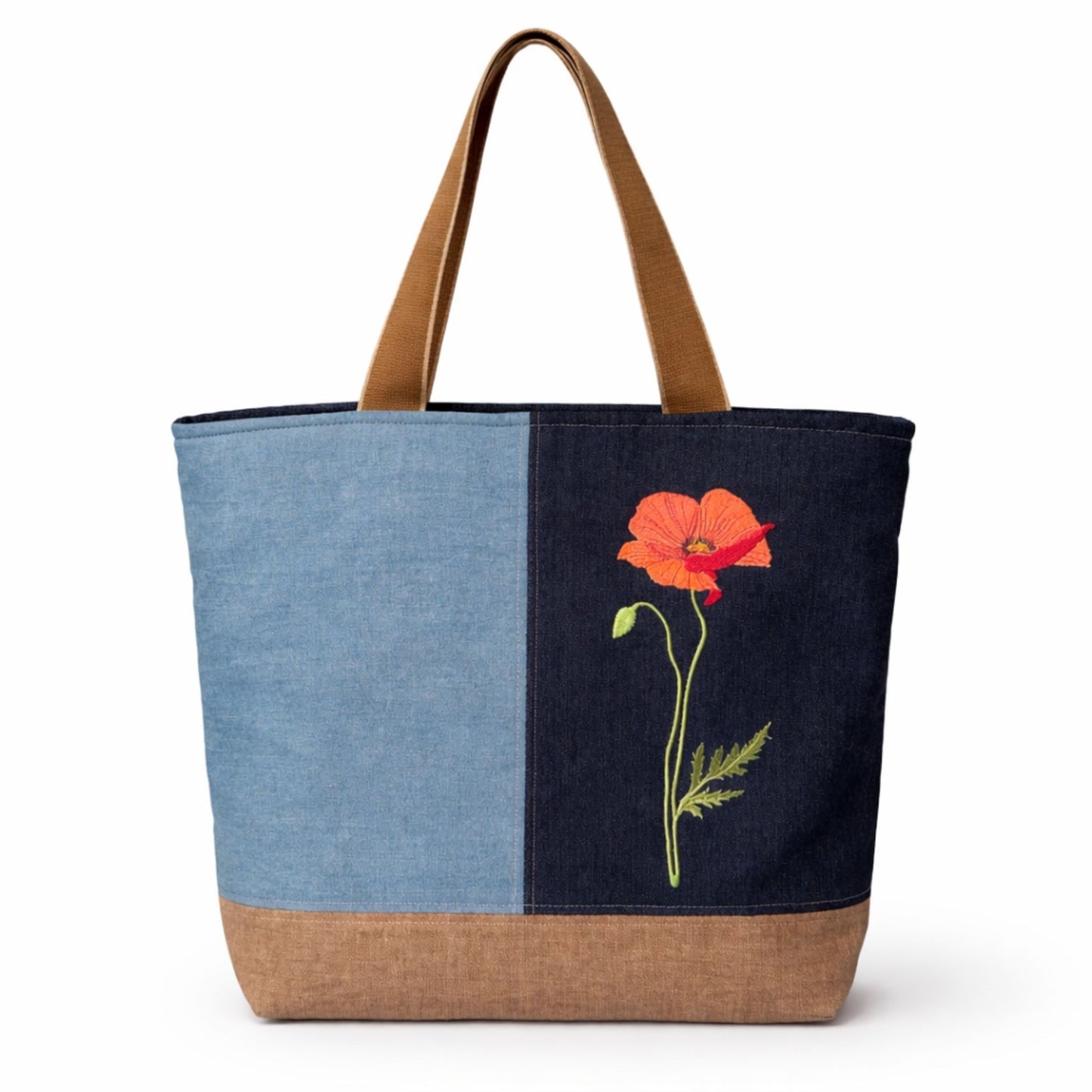 Tote bag with denim, brown, and navy sections, featuring an embroidered red flower on a white background.