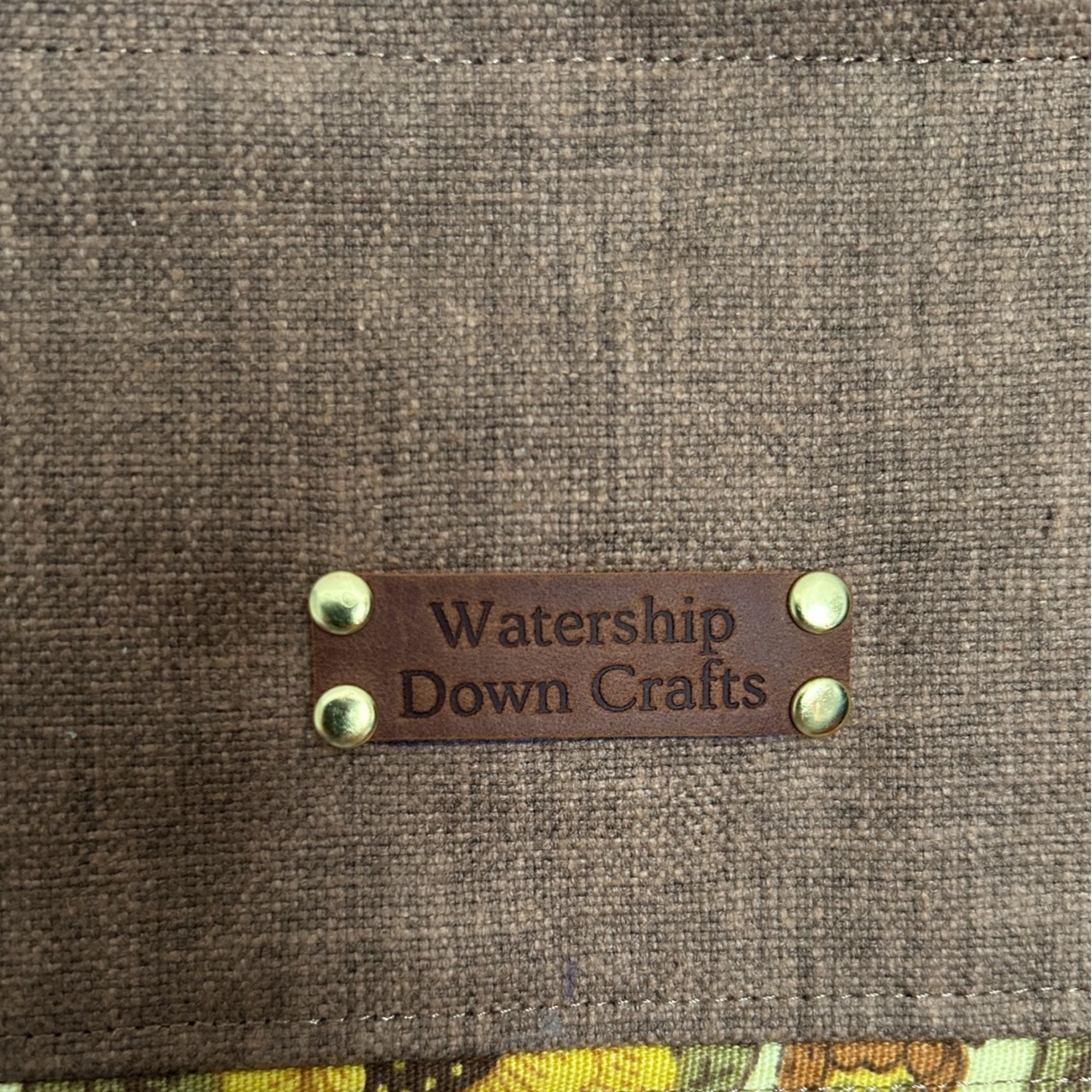 Brown fabric surface with a leather label reading 'Watership Down Crafts'.