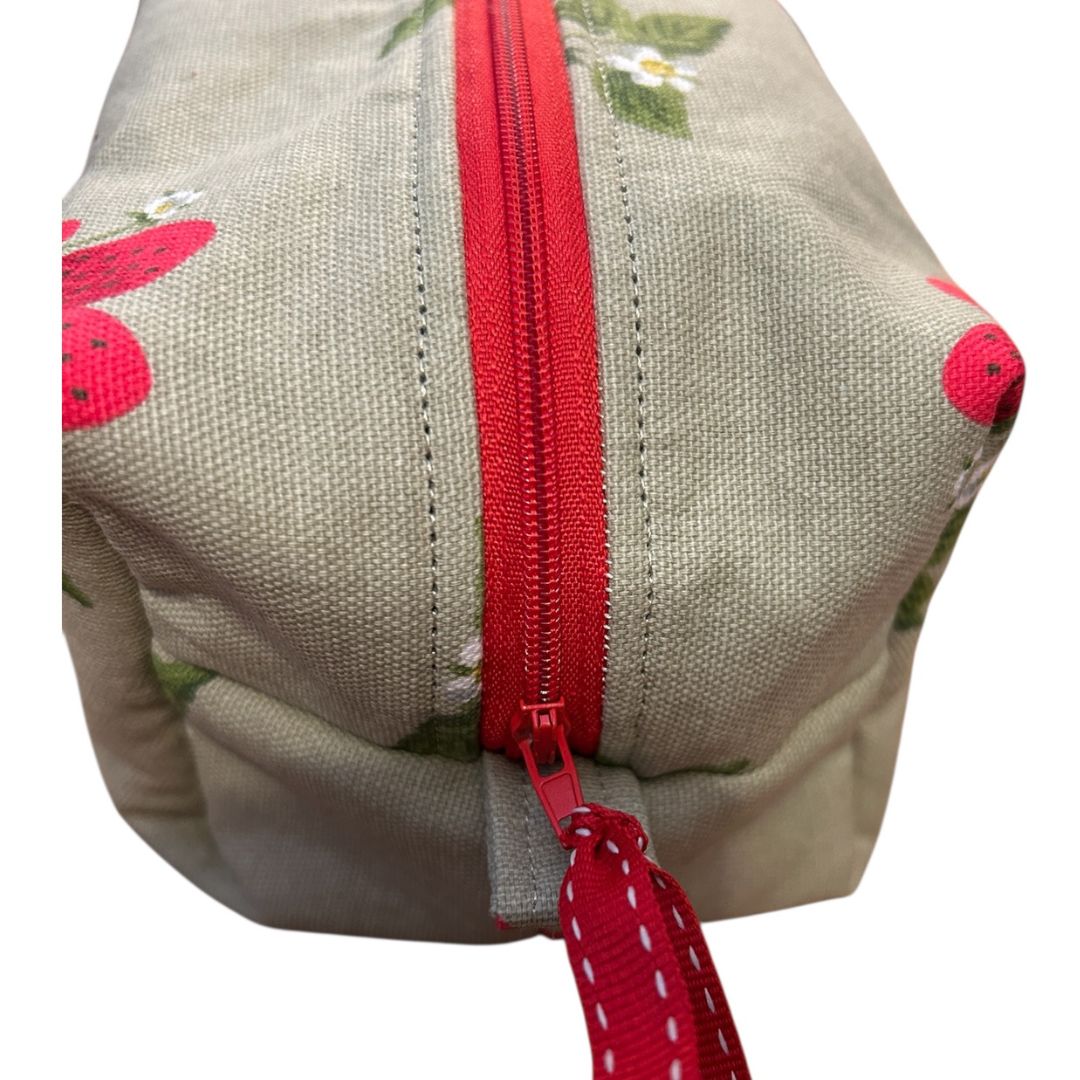 Close-up of red zip and stitching detail on handmade makeup bag in Sophie Allport strawberry fabric by Watership Down Crafts.