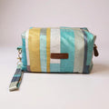 Front view of a boxed makeup pouch in soft aqua, mustard, and cream striped fabric with a matching wrist strap and Watership Down Crafts label.