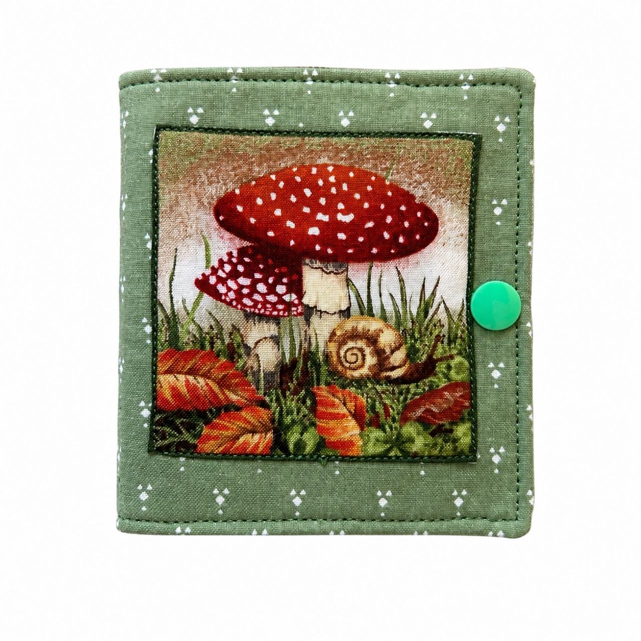needle case with a red mushroom design on a green background
