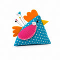 Colorful chicken-shaped pin cushion with pins on a white background