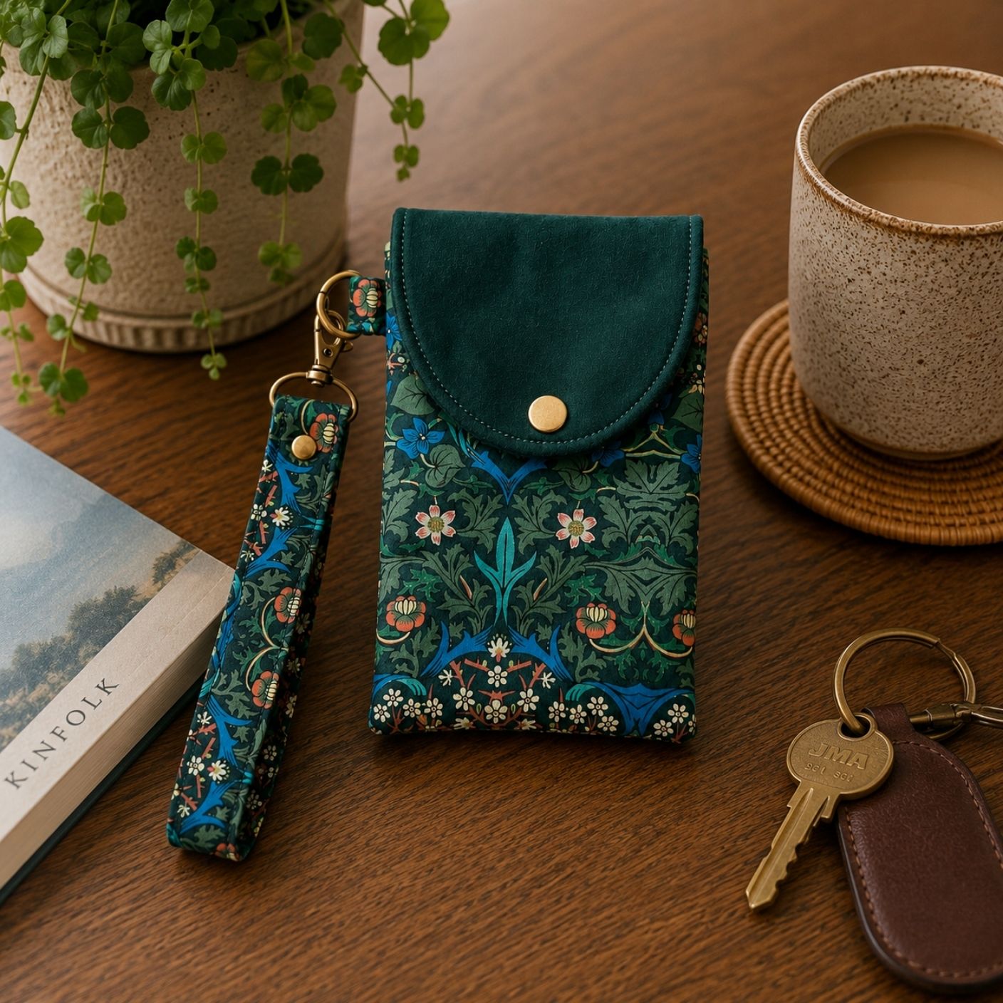 Decorative phone case with floral pattern on a wooden surface with a cup of coffee and plant.