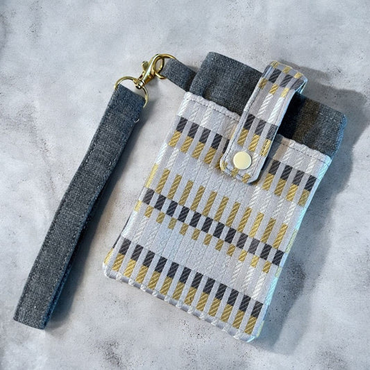 Front view of a handmade phone case in yellow, silver, and grey print with wristlet and snap closure
